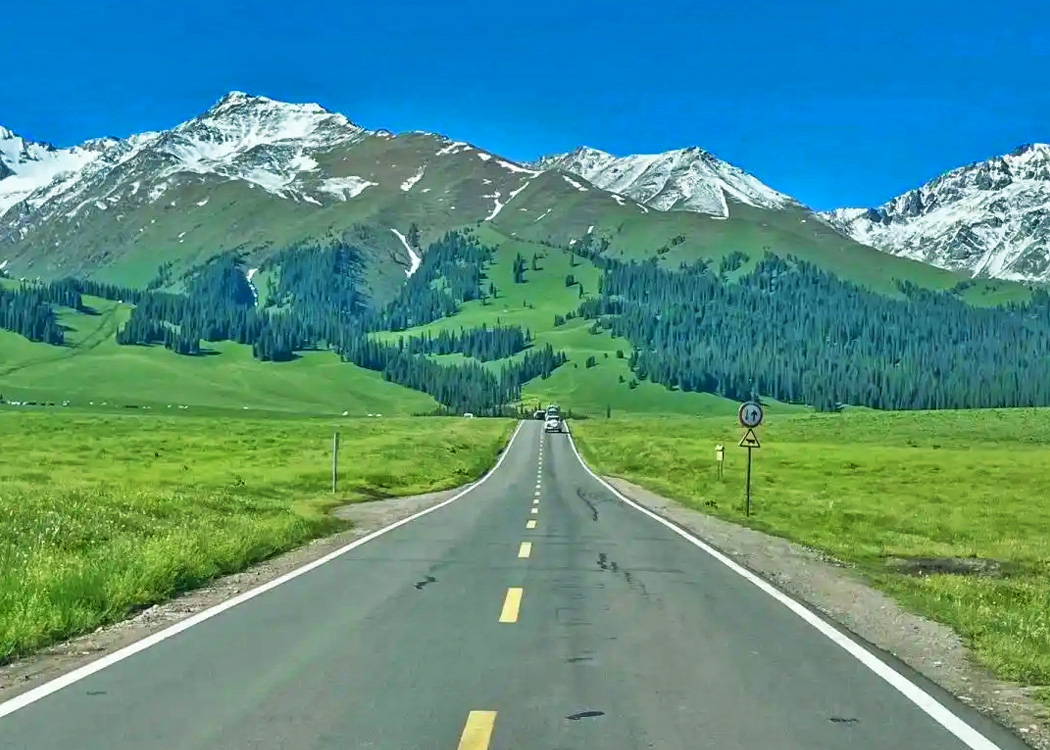 新疆夏季旅游，游客在湖边自驾旅行拍照，远处雪山与蓝色湖泊风景